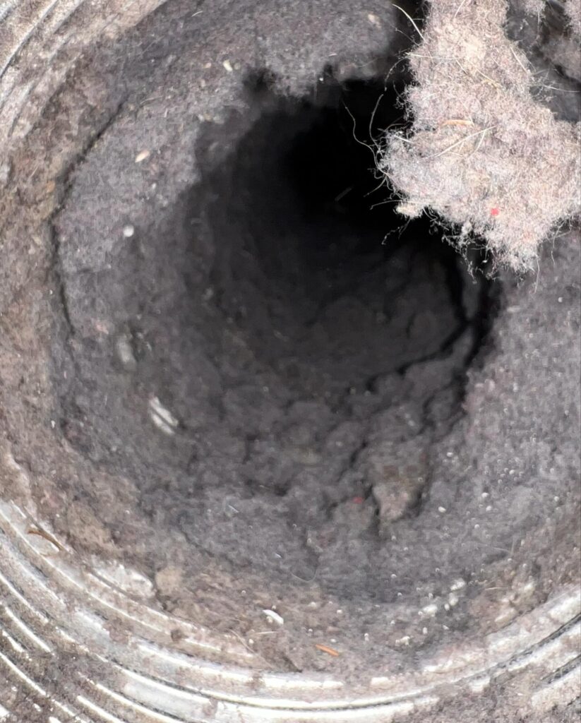 Closeup of dusty, lint-filled dryer vent duct