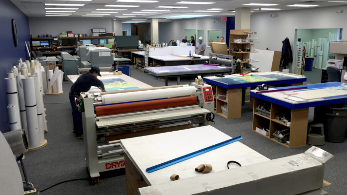 Printing workshop with wide-format printer and packaging boxes.