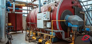 Large industrial boilers lined up inside a boiler room with pipes and equipment attached.