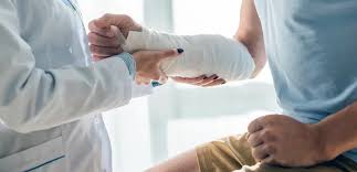 A doctor supports a patient’s bandaged arm during an exam.